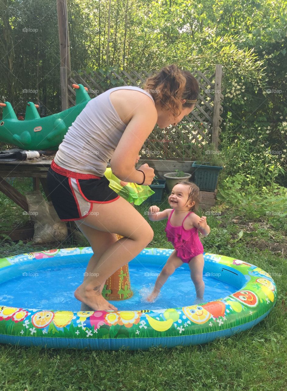 Mother playing with cute child inflatable pool