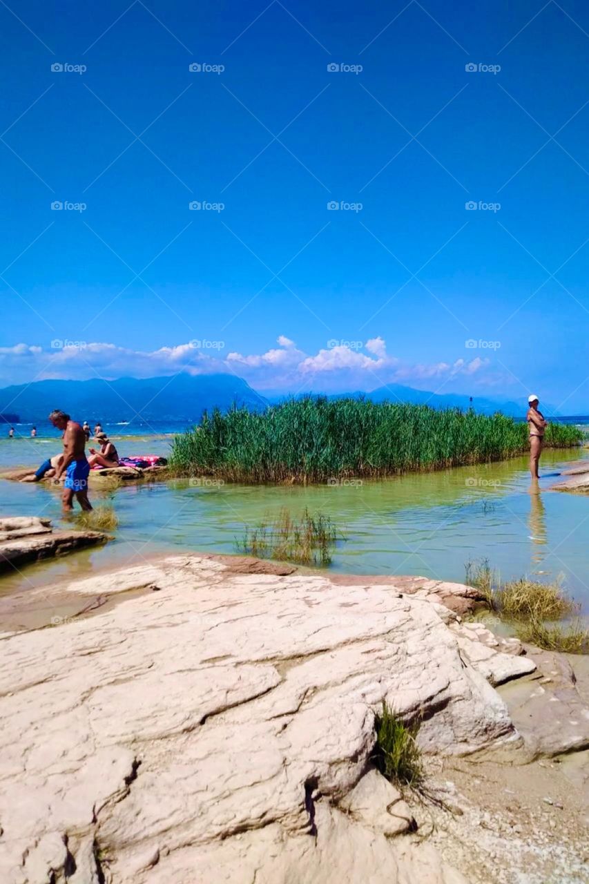 This picture perfect scenery comes to us from the „Lake Garda“ or „Lago di Garda“ in the native tongue in „Northern Italy“. It is located near the „Alps“, the mountain range that can be seen faintly in the background. 2023. Hypnotic Productions