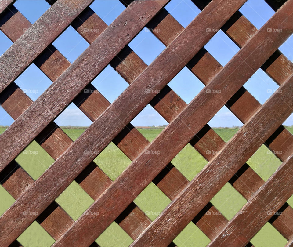 Wood fence with grass field and blue sky background.
