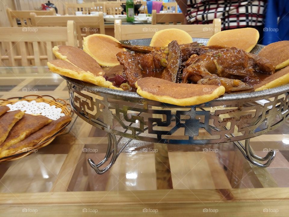 Fried fish in a spicy sauce on metallic dish.