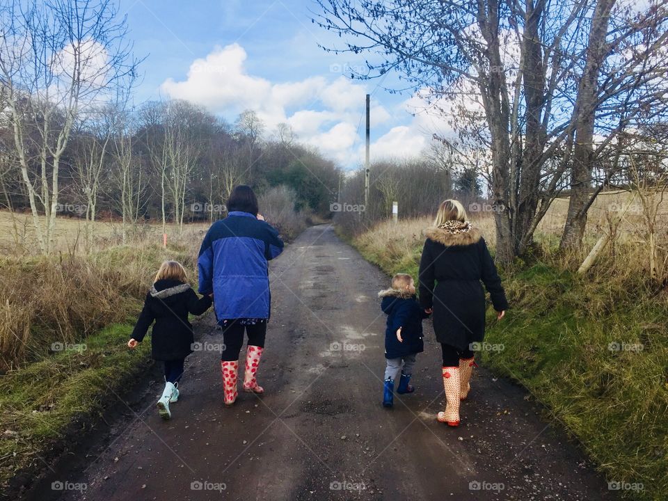 Family walking from behind in Wellington boots in the countryside 