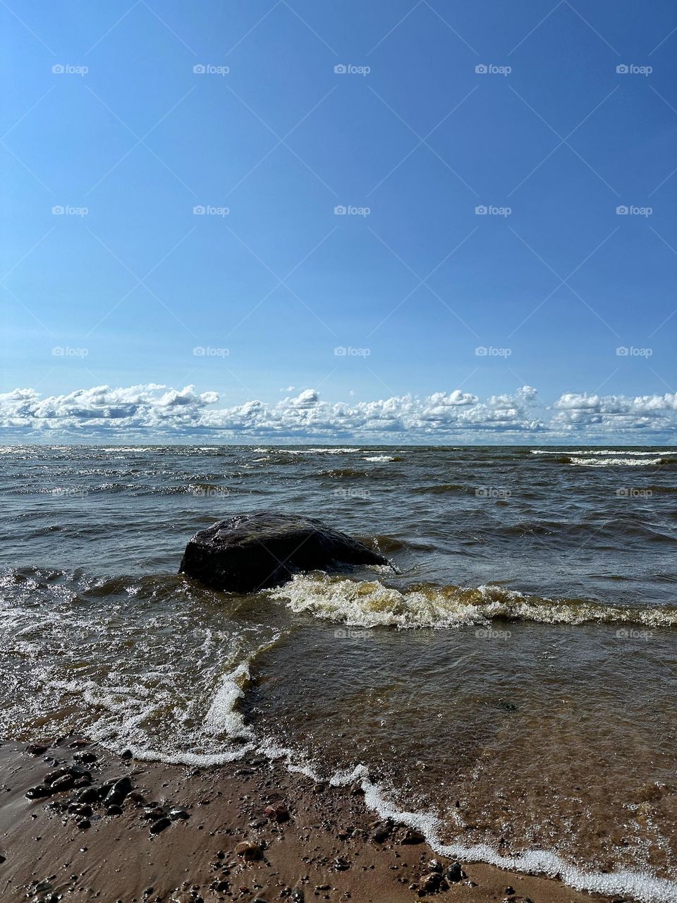 Big stone in the big waters of gulf under blue sky 