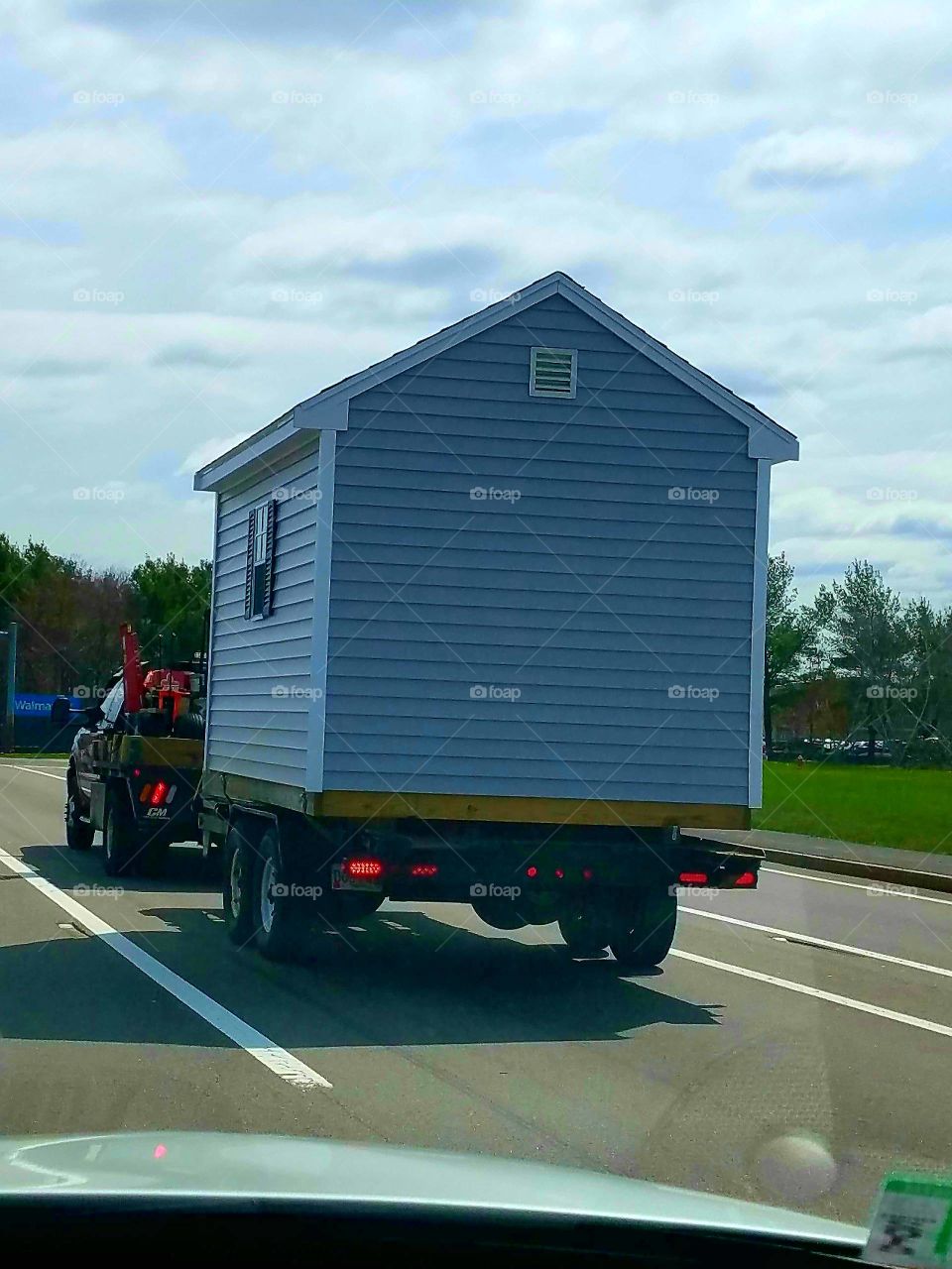 Truck was hauling this small building or shed on a flatbed. Got this pic as it was driving down road.