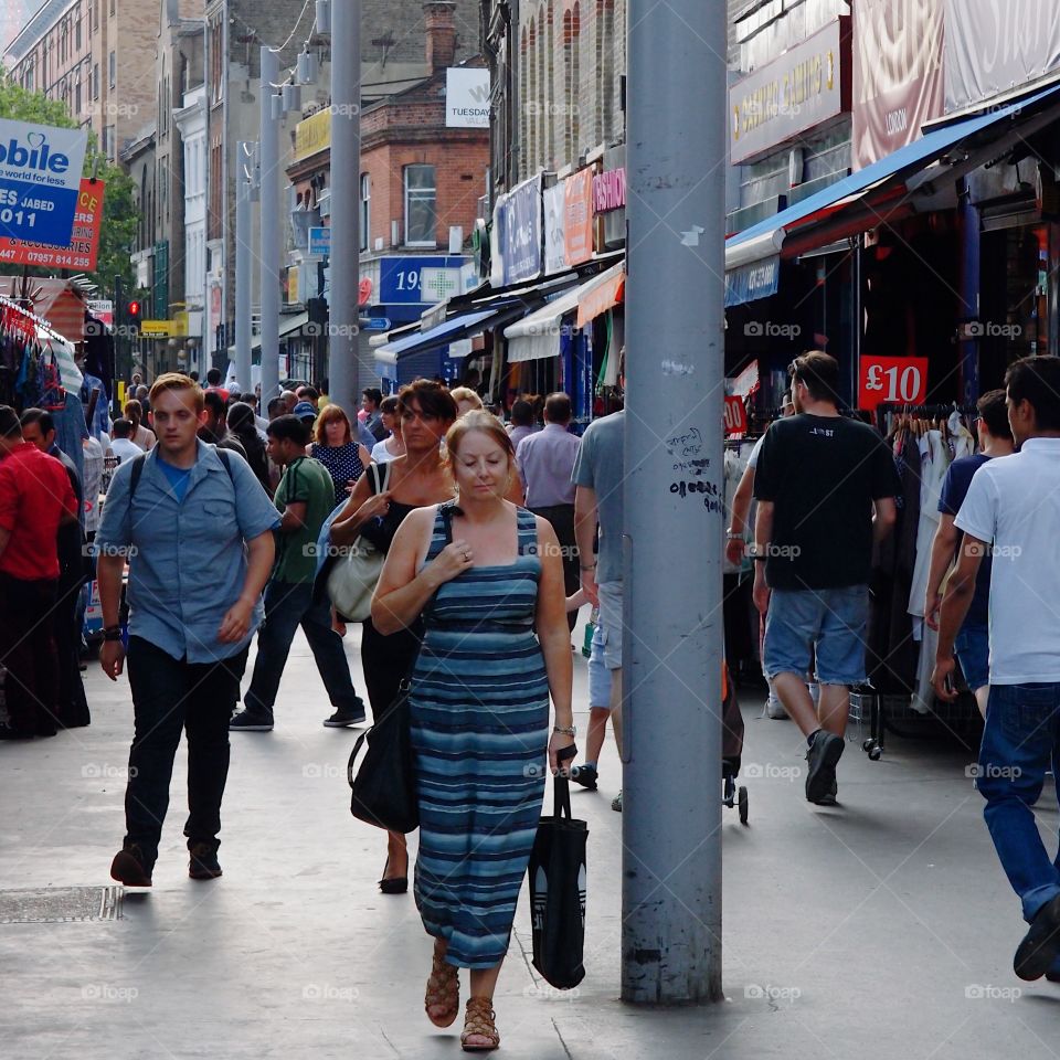 Crowds of people out walking and shopping on European sidewalks on a summer day. 