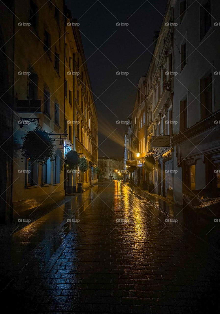 Empty European street in the evening after the rain, warm light, paving stones reflecting the light, no people, calm atmosphere of the peaceful evening, Świdnica, Poland