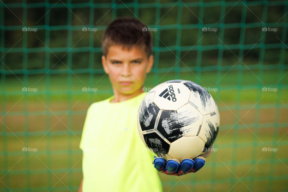 A soccer ball on the hand of a young football player. close-up