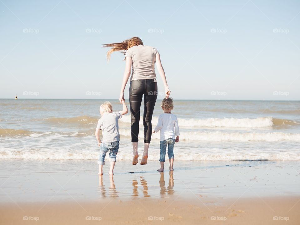 Mother and two kids jumping on beach