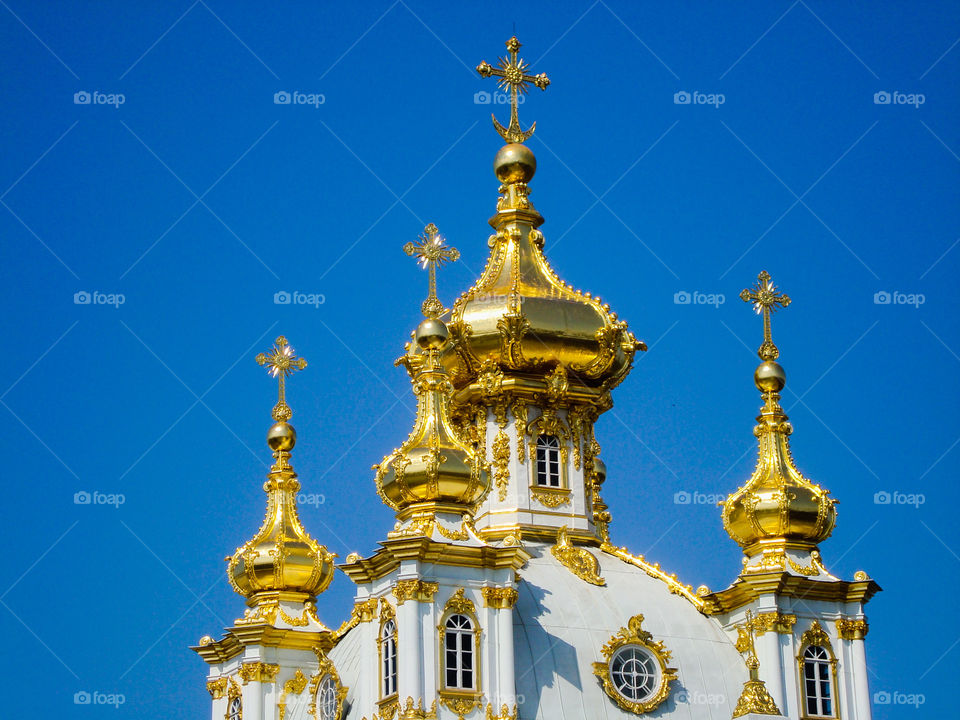 Gold capped church spire against a deep blue sky in St Petersburg Russia