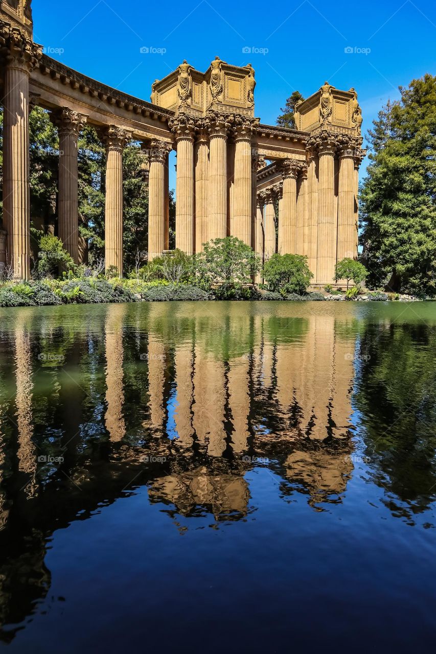 Palace of fine arts in San Francisco California on a beautiful sunny afternoon in the spring, with the Greco Roman style columns reflecting in the lagoon like a mirror 