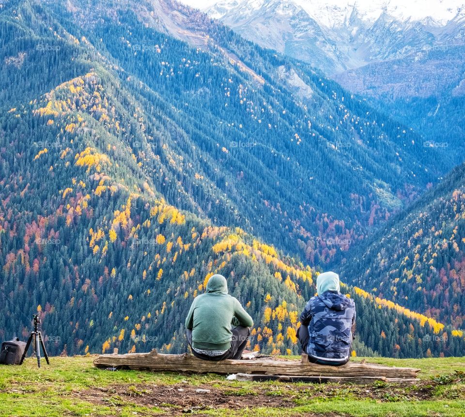 Tourists relax in front of autumn scene in the valley of Caucasus Mountains in Georgia