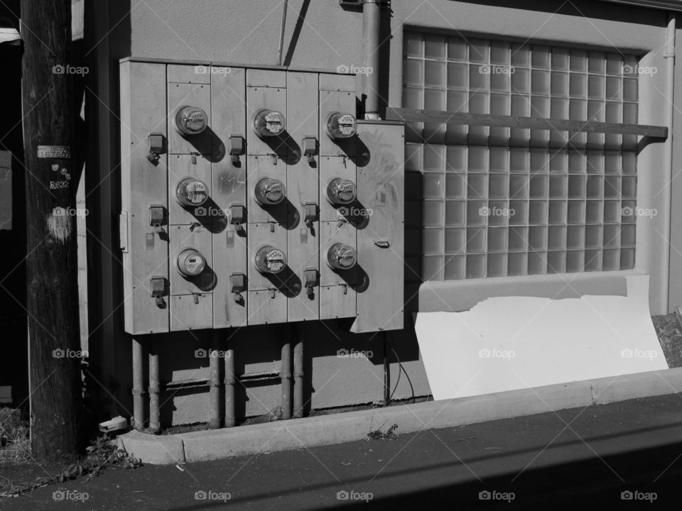 A bank of utility meters on the side of an old building in a city on a sunny summer day in Central Oregon. 