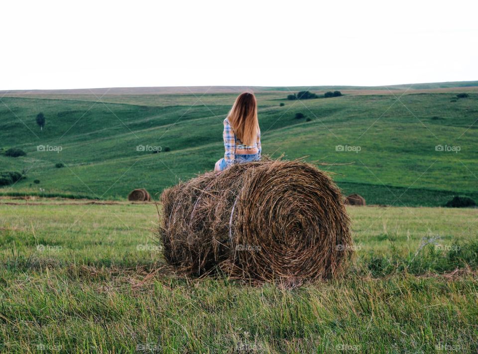 Woman sitting on hay bale at farm
