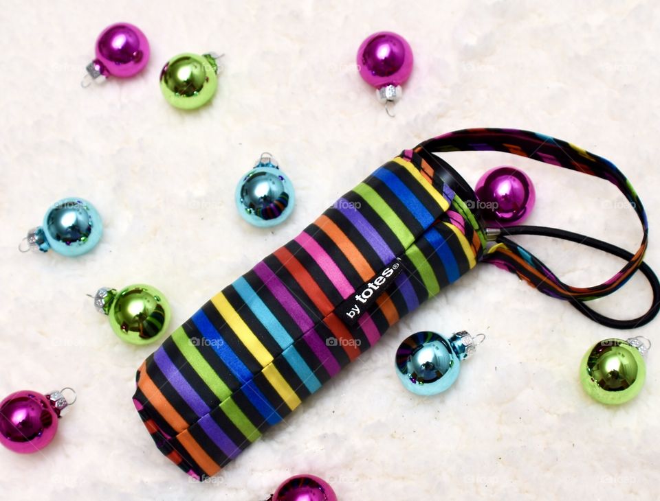 Totes travel size striped umbrella with Christmas bulbs by it