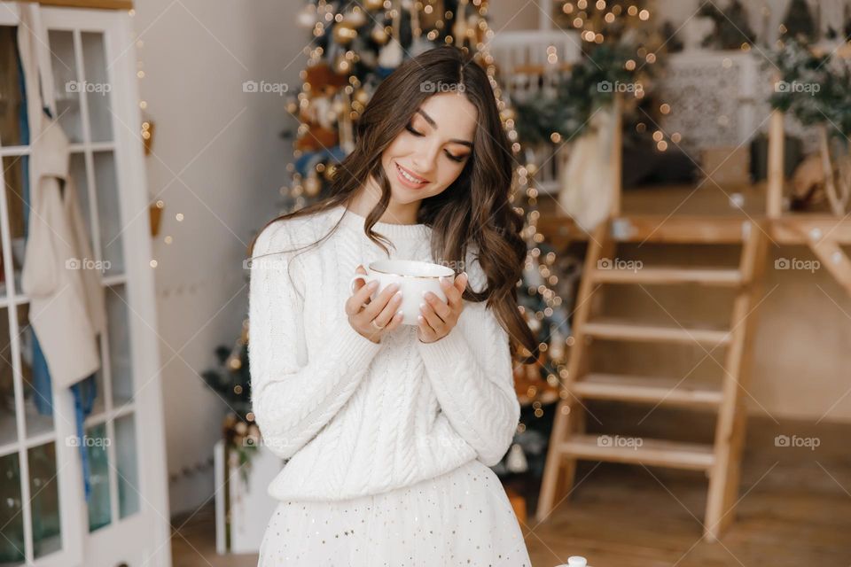 Beautiful brunette girl in white clothes holding cup of tea