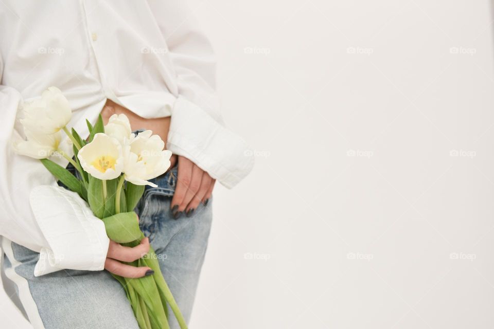 Part of the body of a girl in white shirt who holds in her hands a bouquet of f white tulips isolated on a white background. Concept gift for Valentine's day, birthday, 8 March, mother day. Copy space