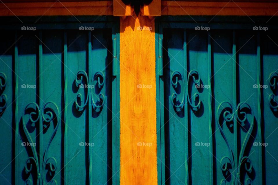 Turquoise gate on orange colored wall