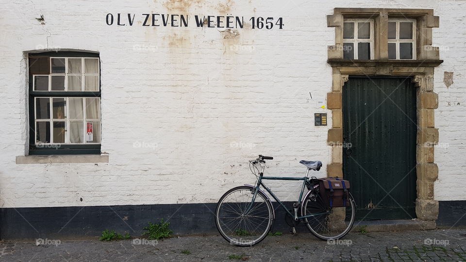 A bicycle is left leaning against a wall on Driekroezenstraat, Bruges, Belgium