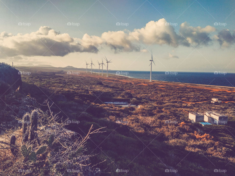 birds eye view of giant electric windmills on the coast