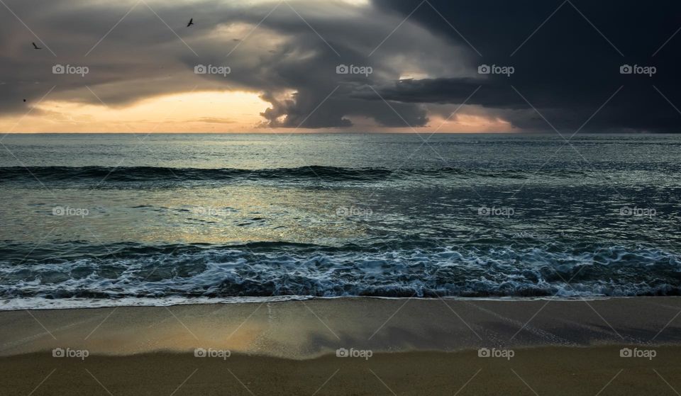 A storms heads in from the Atlantic Ocean obscuring the sunset, as seen from the beach at Nazaré, Portugal. 