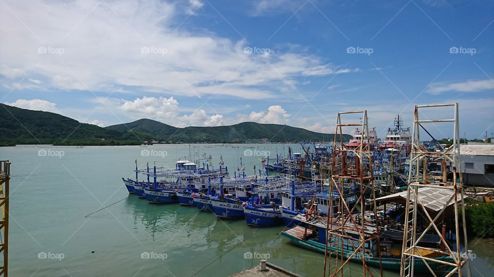 Fishing boat at pier on lake in Songkhla, Thailand with blue bright sky and green water