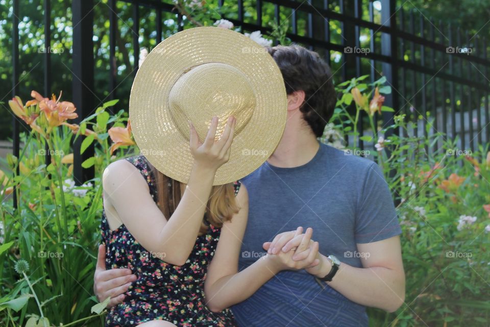 A couple shares a kiss behind a straw hat