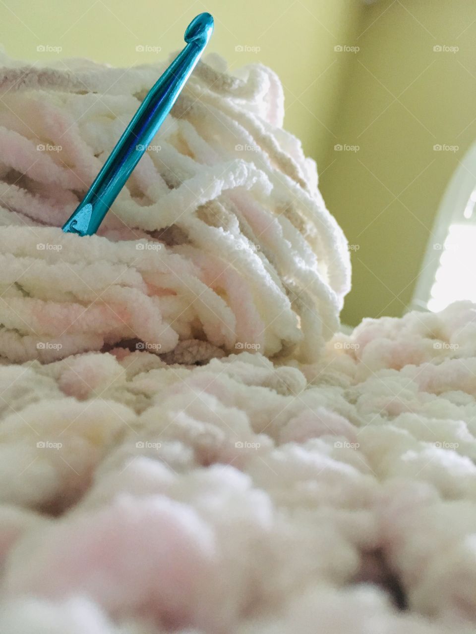 Beautiful soft colored yarn with blue hook crocheting a blanket 