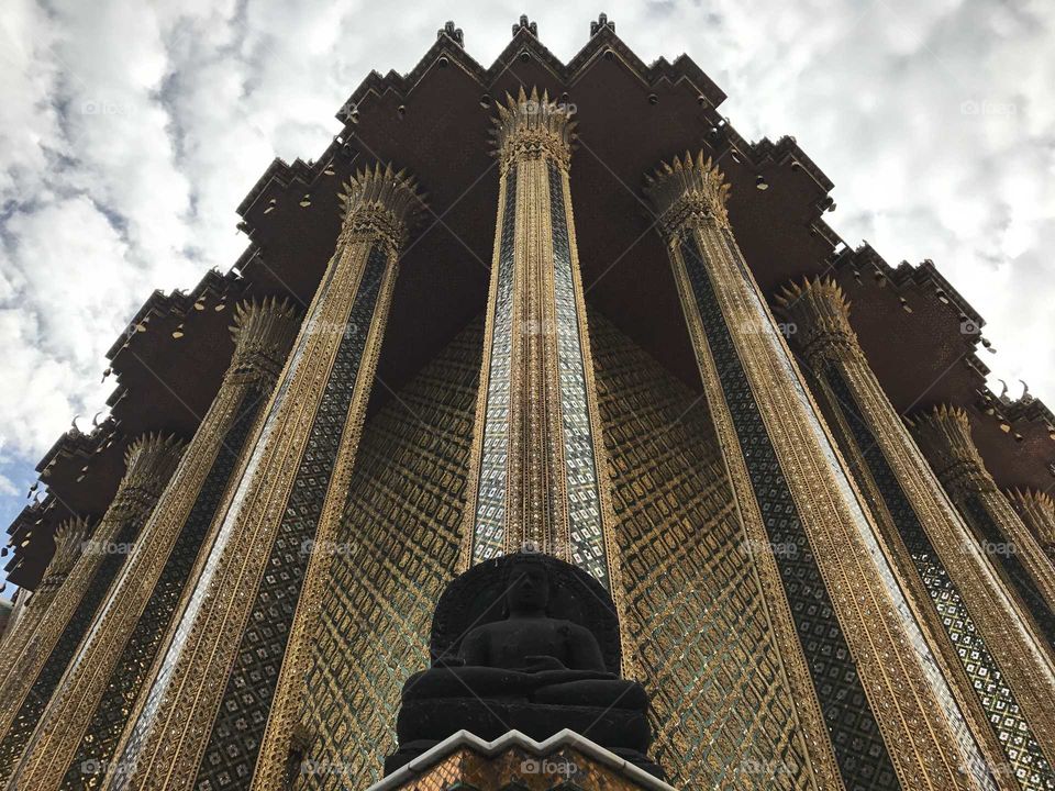 A beautiful golden temple in bangkok with a grey sky in the background