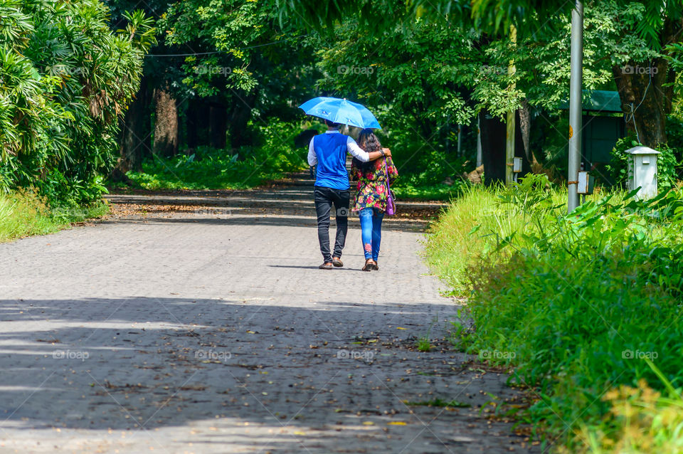 Portrait of two joyful young loving Couple walking in a green autumn park on a romantic summer day. Pre-wedding marriage engagement concept. Togetherness composition. Botanical garden, Kolkata, India