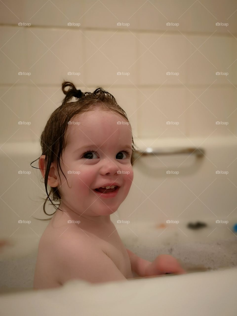happy toddler in the bath with wet hair