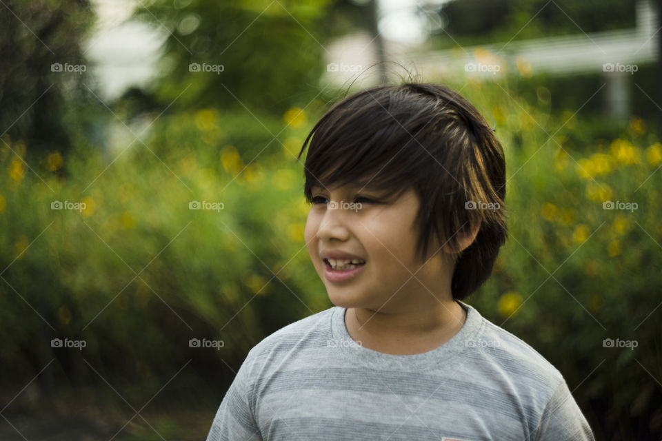 outdoor portrait of happy young eurasian boy on a blurry out of focus bokeh foliage background