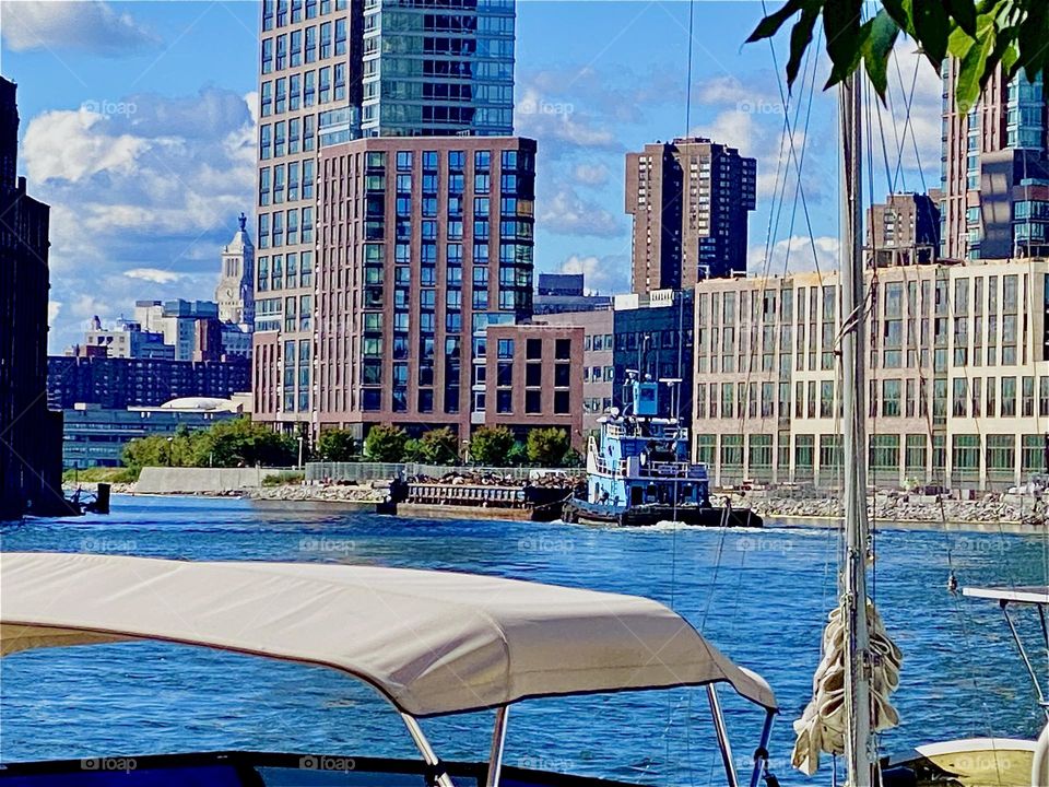 This is the large industrial barge driving away on the „East River“ at „Newtown Creek“ by the „Pulaski Bridge“ in LIC, Queens on a bright sunshiny day in October 2023. Hypnotic Productions