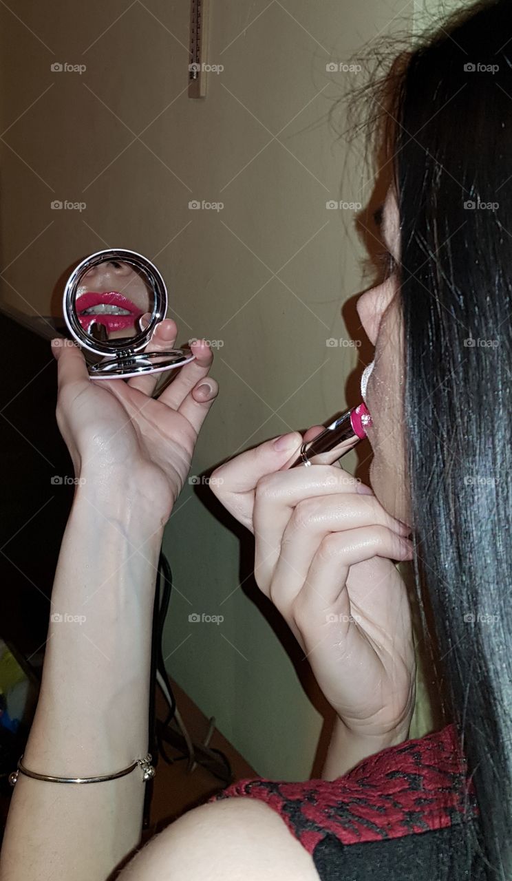 Girl apply lipstick in the mirror red lips