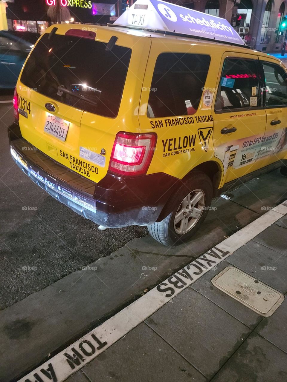 Yellow taxicab waiting on the street in San Francisco California at the taxicab loading zone at night 