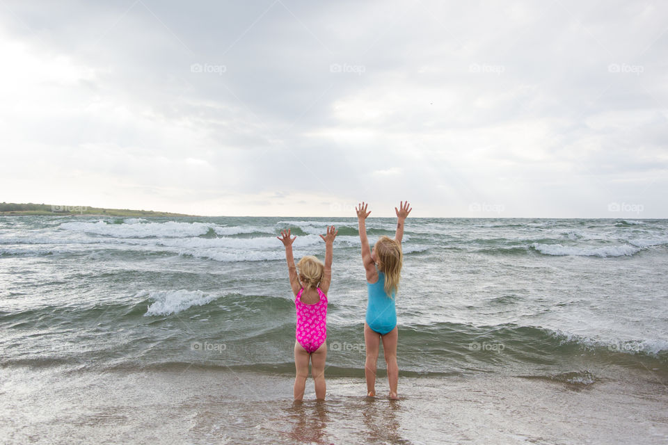 Twi sisters playing at the beach of Tylösand outside Halmstad in Sweden. It's about to get stormy weather but the girls is having fun swimming and playing in the water.