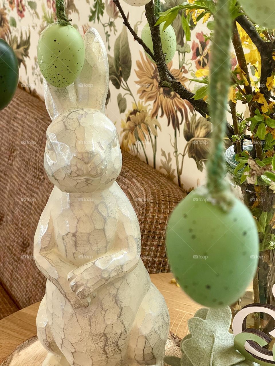 wooden sculpture in the shape of a rabbit under an easter tree decorated with egg-shaped balls