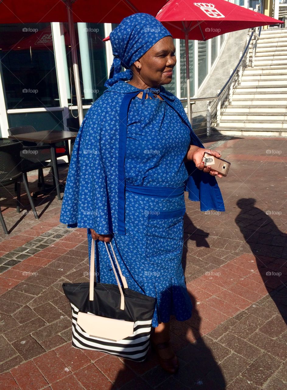 African lady wearing shweshwe print outfit smartly dressed at the V&A Waterfront in Cape Town,South Africa 