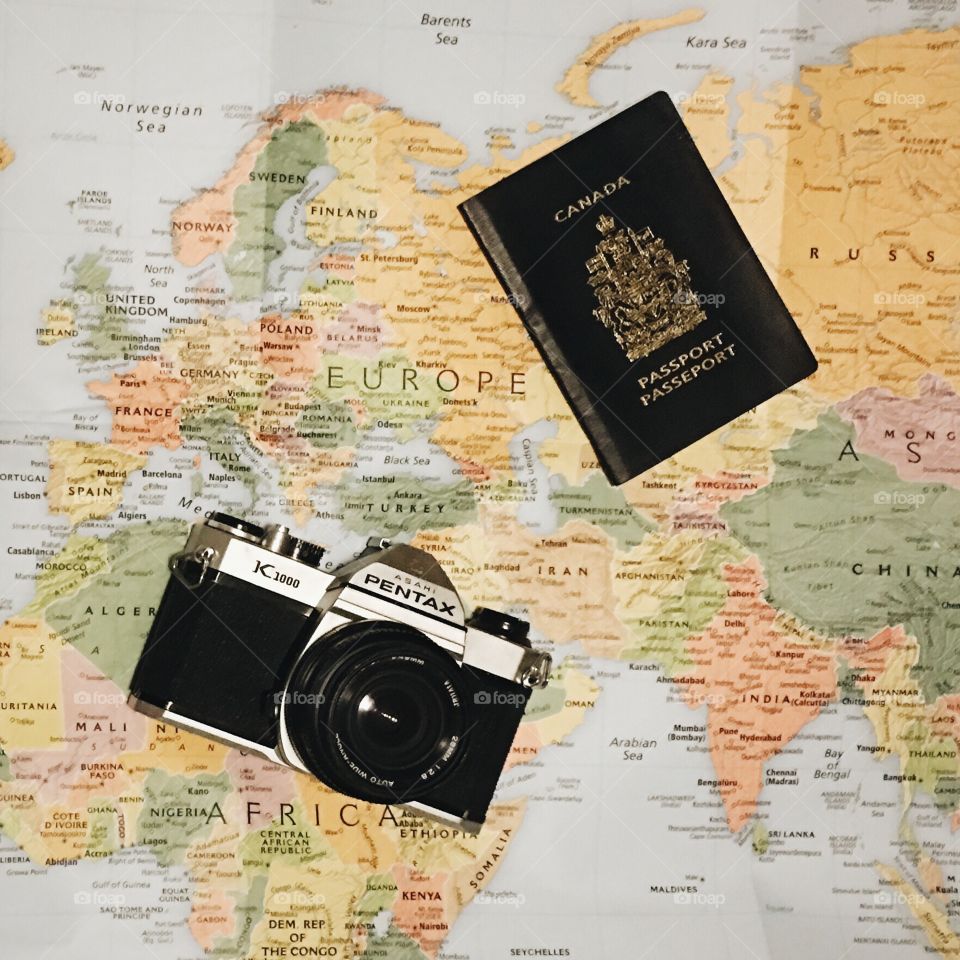 Vintage camera and Canadian passport on map of Europe