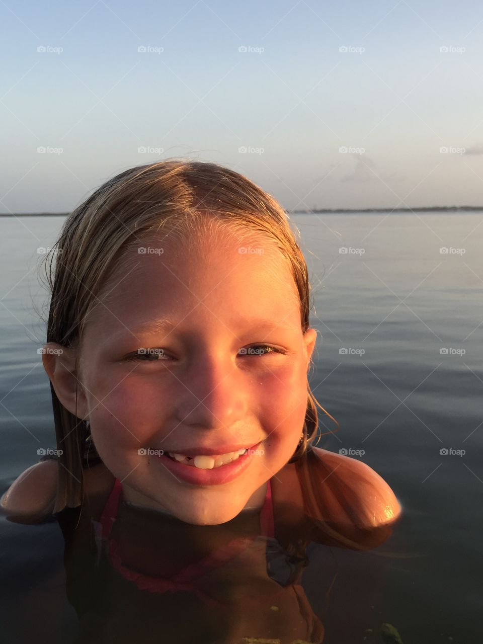 Little girl in the ocean at sunset 