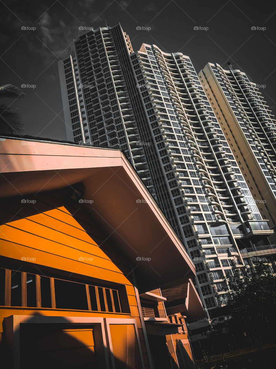 Side by side of the orange small house and the apartment building, the contast makes the great composition.