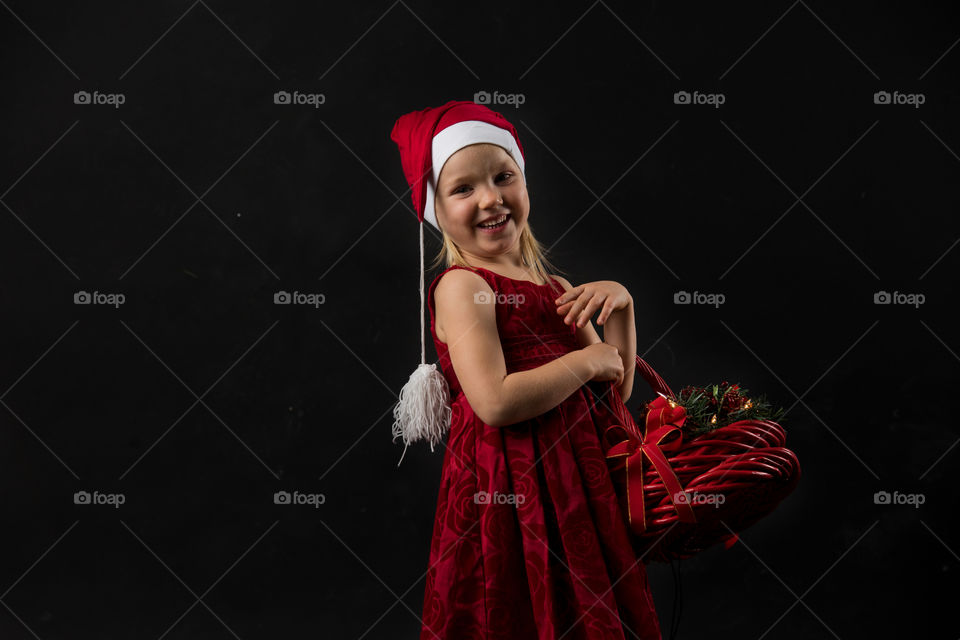 Four year old girl posing in santa dress for christmas.