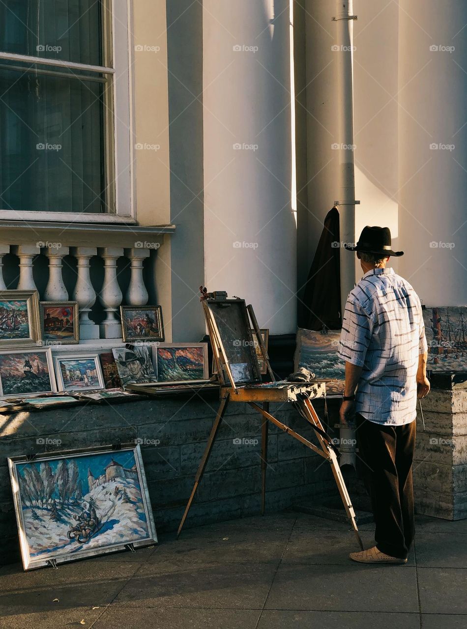 Unrecognisable adult artist on street in summer sunny day