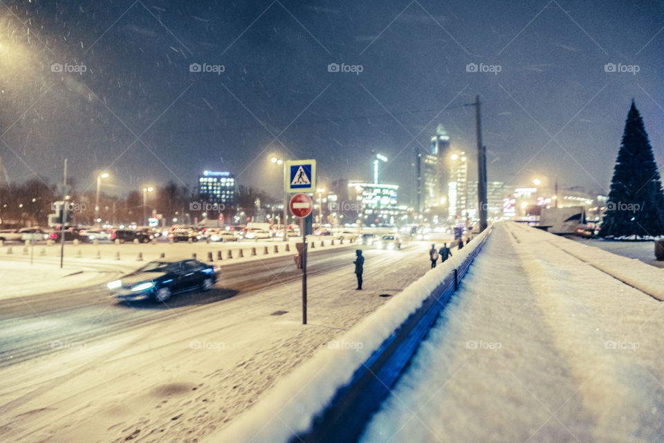 Winter night city lights in snowfall