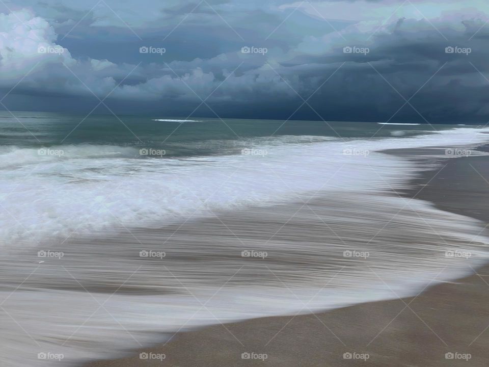 Atlantic Ocean Beach With Time In Motion Long Exposure Of The Waves On The Seashore During A Thunderstorm With Dark Grey Clouds.