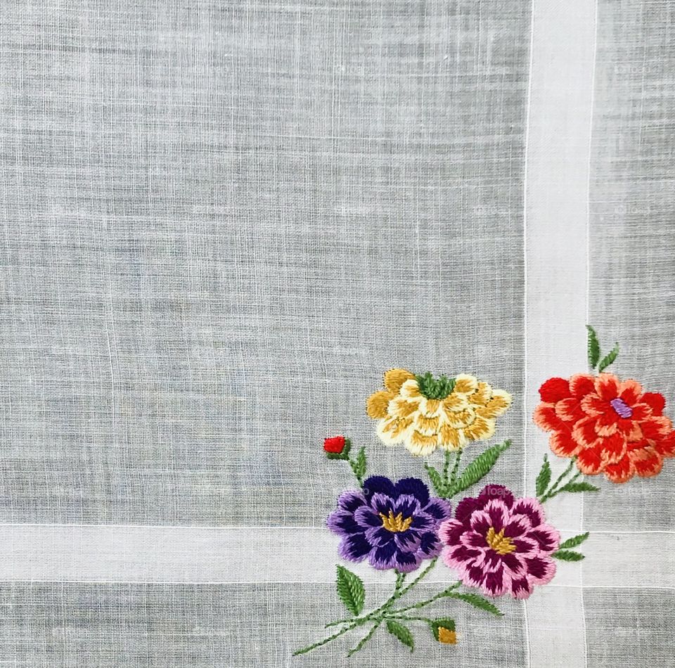 Bright colorful embroidered flowers on plain white fabric background