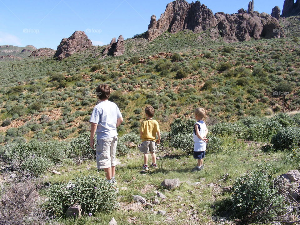 Three boys standing and looking out at the desert valley in Arizona 