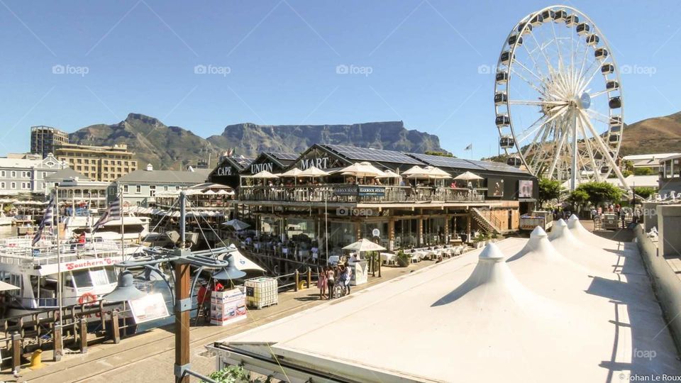 peek of the Big wheel in capetown Waterfront with tablemountain in the background.