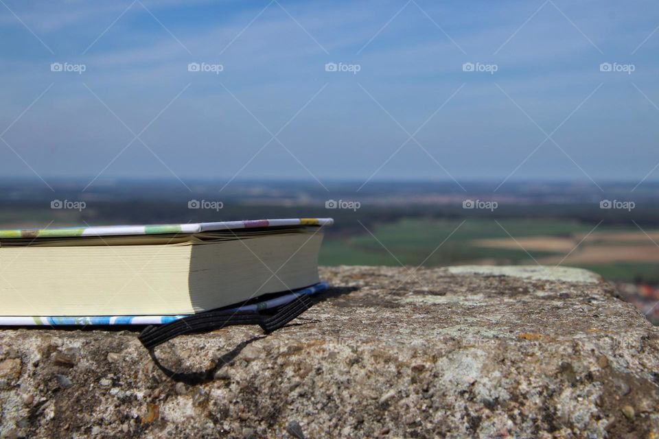 Close-up of a book on a rock with landscape in the background