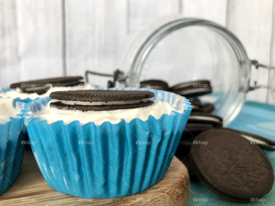 Oreo cookie ice cream cupcakes on a wooden board and white and blue background 