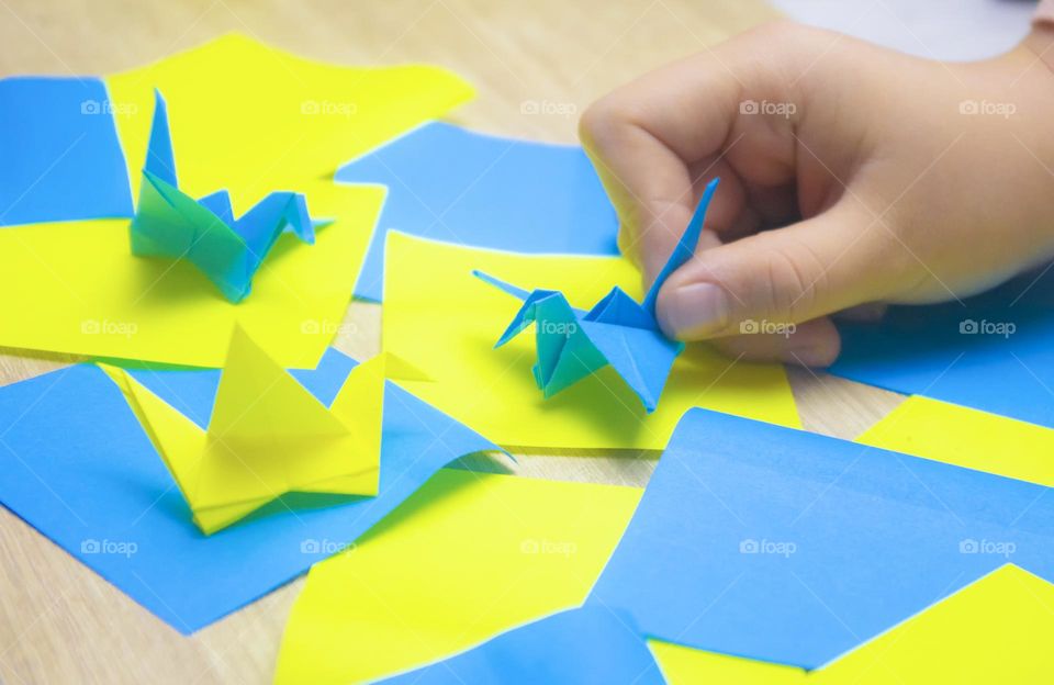 child folds paper cranes