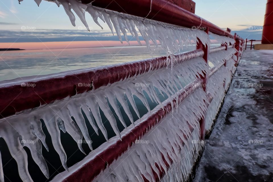 Icicles on red railing at sunset